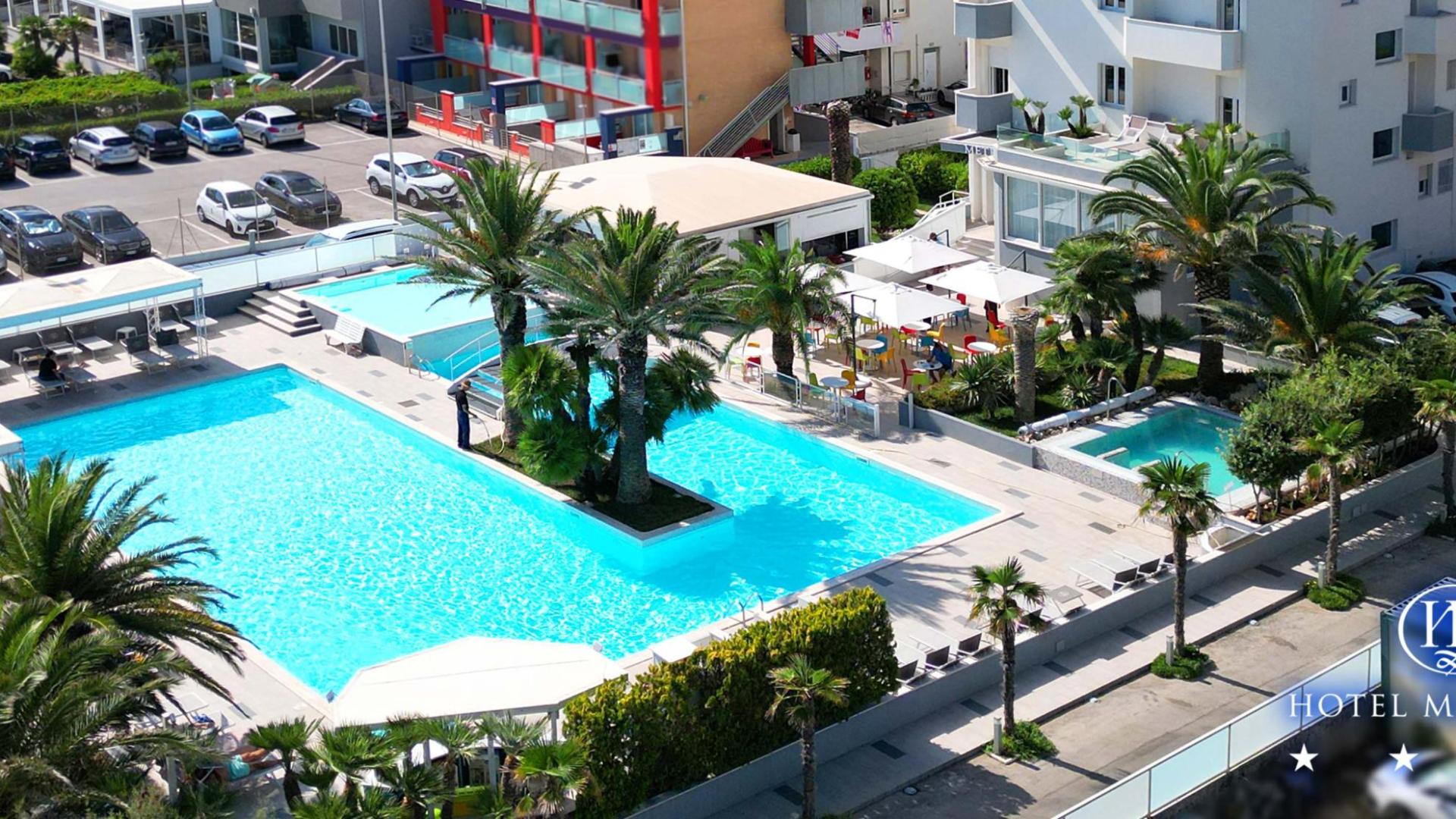 Piscina all'aperto dell'Hotel Metropol con palme e area relax.