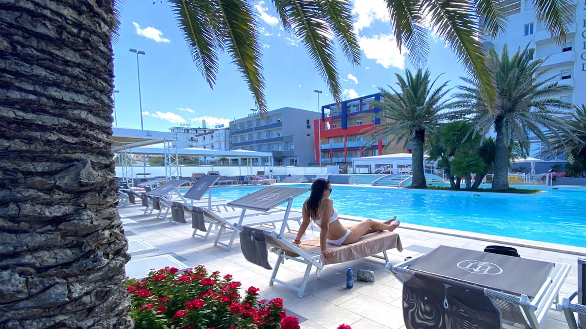 Piscina all'aperto con lettini e palme, Hotel Metropol a Senigallia.