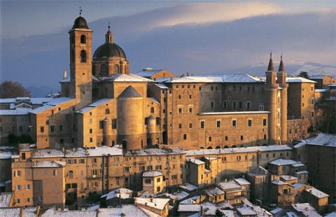 Palazzo Ducale di Urbino, imponente architettura rinascimentale, coperto da neve al tramonto.