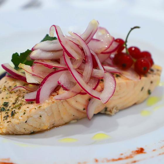 Salmone con cipolle rosse, ribes e prezzemolo, guarnito con olio d'oliva.