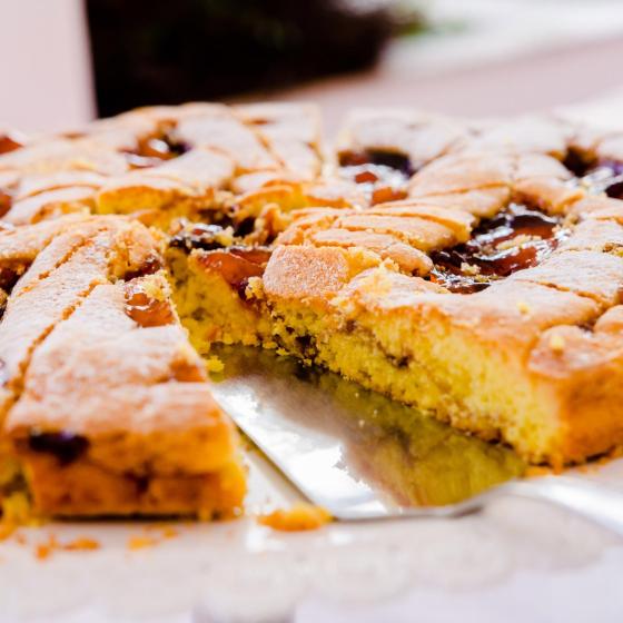 Crostata con marmellata e zucchero a velo, tagliata e servita su un vassoio.