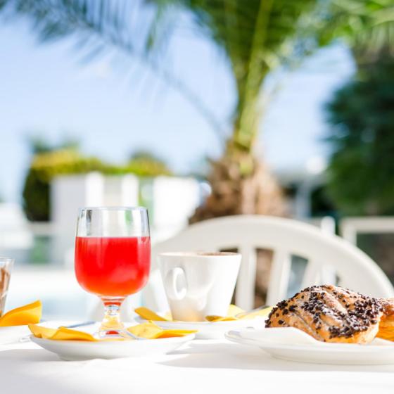 Colazione all'aperto con succo, caffè e dolci, sotto una palma.